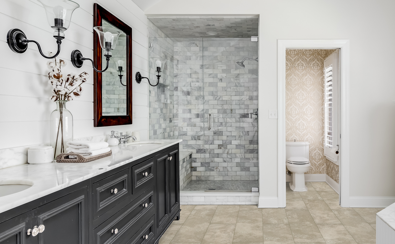 marble subway tile shower surround with neutral brown tile flooring in bathroom